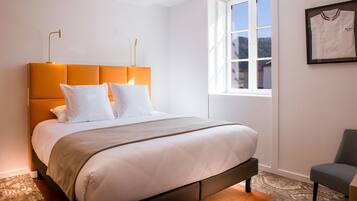A neatly made bed with a headboard, a bedside lamp, and a framed item on the wall.