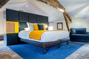 A modern bedroom with a large bed, built-in storage, and a rustic ceiling beam. - Logis Hôtel Le Tilia (Joux)