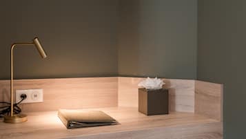 Un escritorio moderno con una lámpara, una caja de pañuelos y un cuaderno.