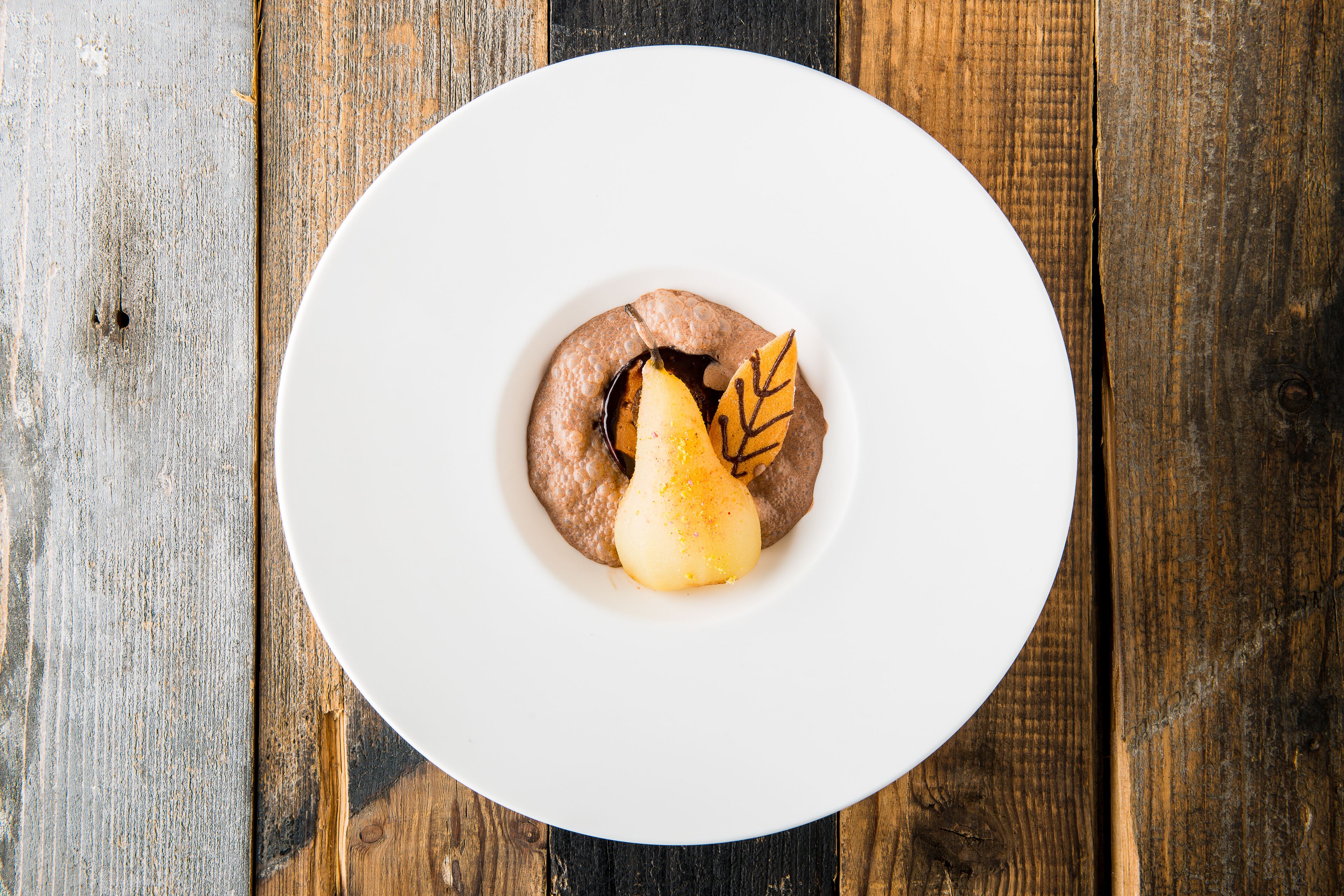 Een wit bord met een dessert op een houten tafel.