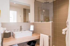 A modern bathroom with a white sink, mirror, and shower. - Logis Hôtel Le Tilia (Joux)