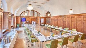 A conference room with long tables, green chairs, and wooden paneling. - Inklusionshotel PHILIPPUS Leipzig (Leipzig)