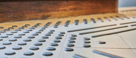 A close-up of a tactile paving surface with raised dots and lines, likely designed for visually impaired individuals.