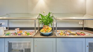 A buffet setup with various food items and a central plant. - Inklusionshotel PHILIPPUS Leipzig (Leipzig)