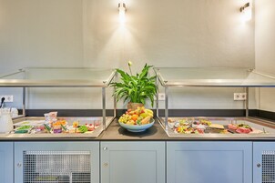 Montaje tipo bufé con diferentes alimentos y una planta en el centro.