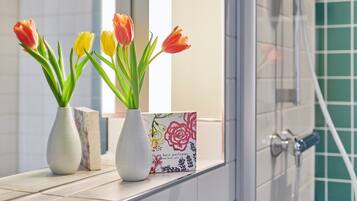 Two vases with tulips on a bathroom counter.