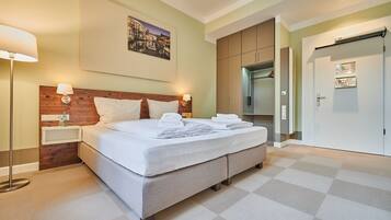 A hotel room with a bed, a nightstand, a lamp, a wooden headboard, a painting, a wardrobe, and a door with a sign.