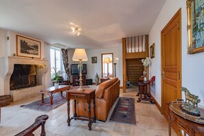 A spacious living room with a fireplace, leather sofa, wooden coffee table, and a television. - Charming house village - heated private pool & outside ktichen (Mézin)