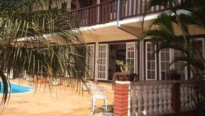 Un edificio de dos pisos con balcón, piscina y palmeras.
