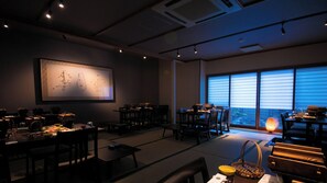 A dimly lit room with tatami mats, traditional Japanese furniture, and a large window with blinds.