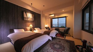 Une chambre d’hôtel avec deux lits, une grande fenêtre, un bureau avec une chaise et une vue sur le paysage urbain.