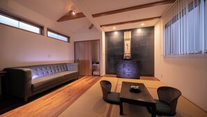 Un salon de style japonais traditionnel, avec un canapé, un revêtement de sol en tatamis, une table basse et un meuble.