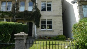 A two-story house with a stone facade, a visible number '68', and a front garden with a metal fence. - Stunning Period Townhouse (Frome)