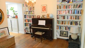 A room with a piano, bookshelves, a chandelier, and a globe. - Stunning Period Townhouse (Frome)