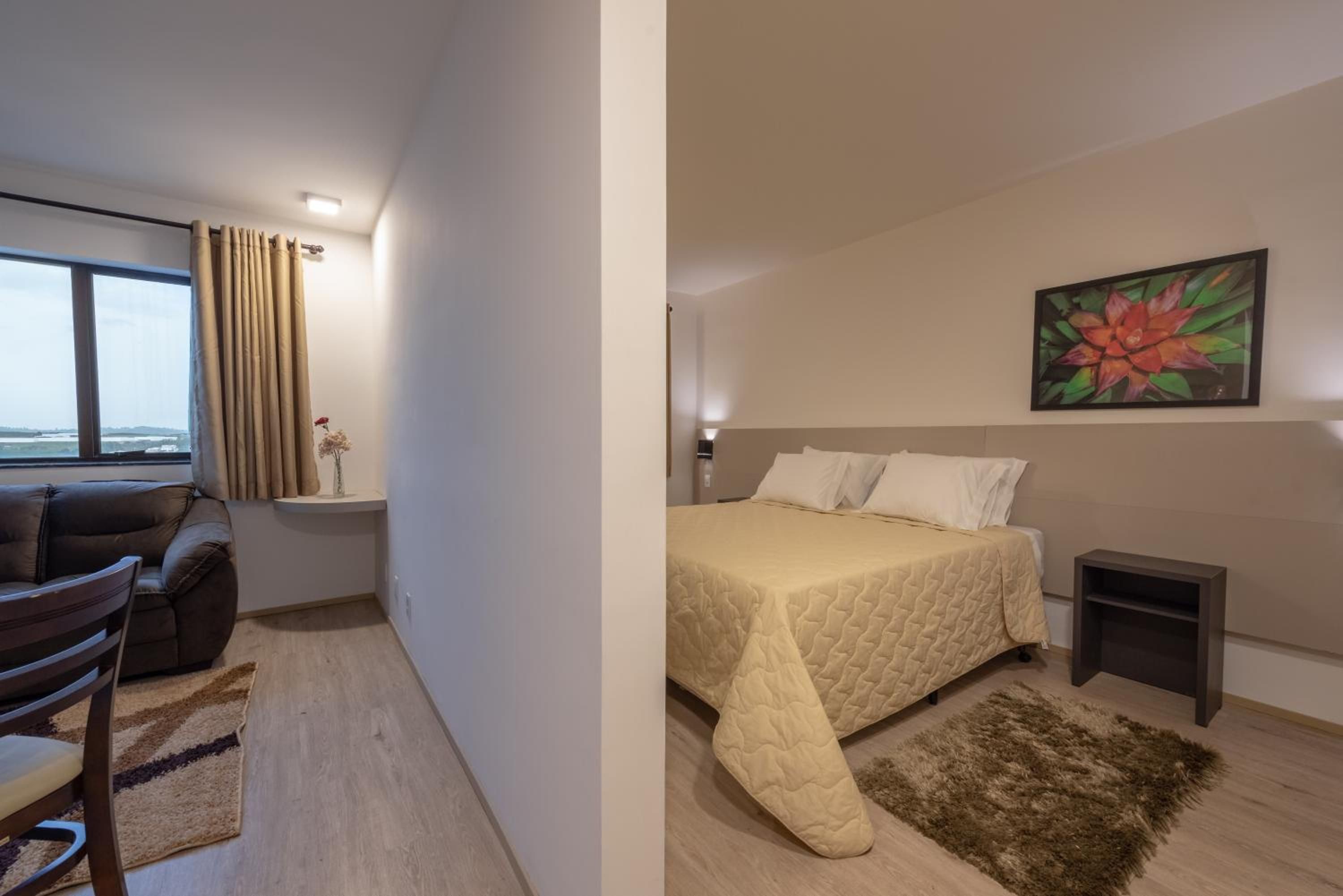 A room with a bed, a chair, a small table, and a painting on the wall.