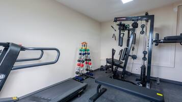 Una palestra con tapis roulant, panche per pesi e diverse attrezzature per allenamento.