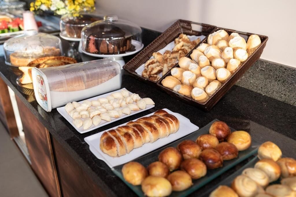 A buffet with various baked goods including bread, pastries, and rolls.