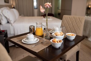 Preparación para el desayuno con una cama al fondo, una jarra de jugo de naranja y tazones de comida sobre una mesa.