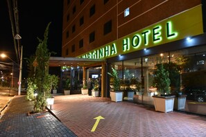 A hotel entrance with a clear pathway marked by an arrow, potted plants, and a well-lit facade. - Via Garden Varginha Hotel (Varginha)