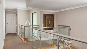 Ein modernes Interieur mit Glastrennwand, Holzstufen und einem gerahmten Kunstwerk an der Wand.