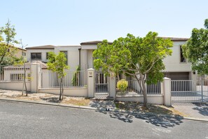 A residential building with a gated entrance, a driveway, and a street in front.