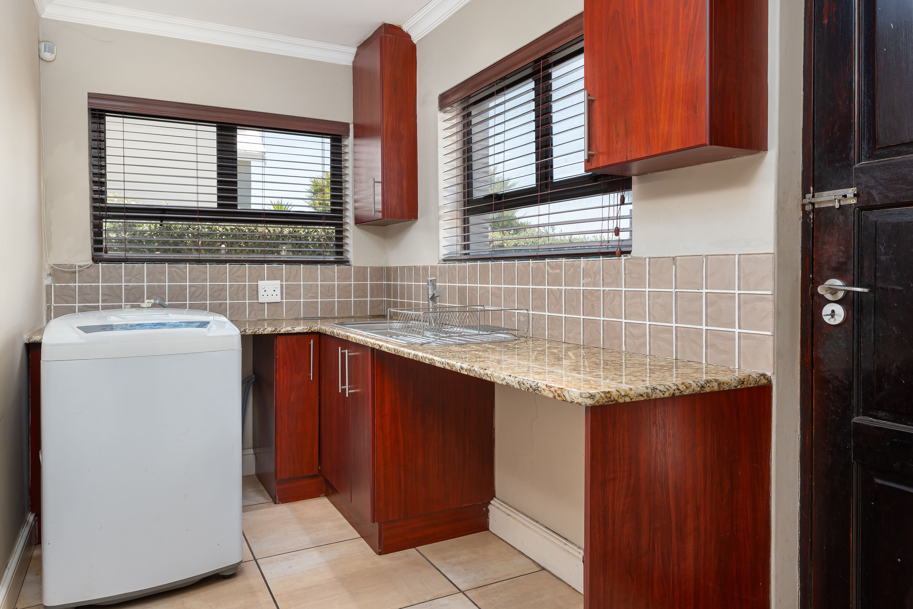 A kitchen with wooden cabinets, a built-in washing machine, and a tiled backsplash.