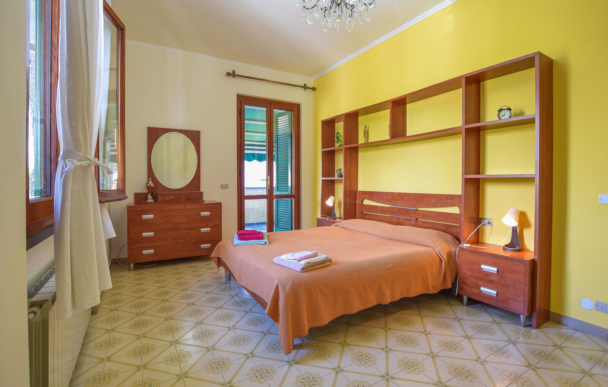 A bedroom with a bed, a dresser, a mirror, and a shelf unit.