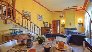 Uma sala de jantar com escada de madeira, um piano e um sofá.