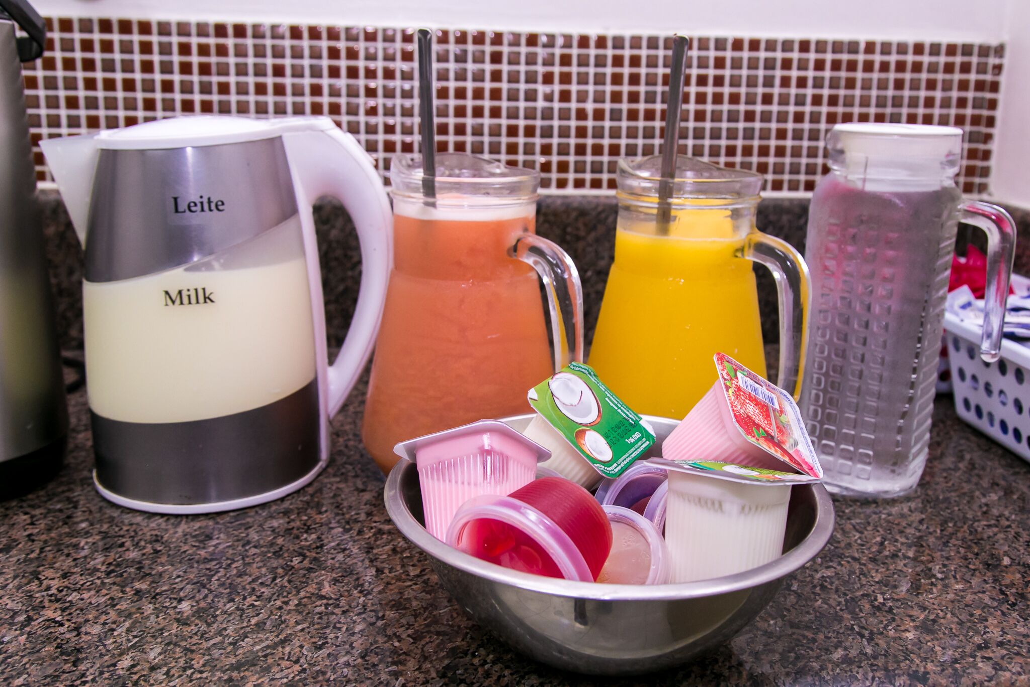 A kitchen counter with various containers and a milk jug labeled "Leite."