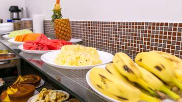 A buffet with various fruits and dishes, including watermelon, pineapple, and bananas.