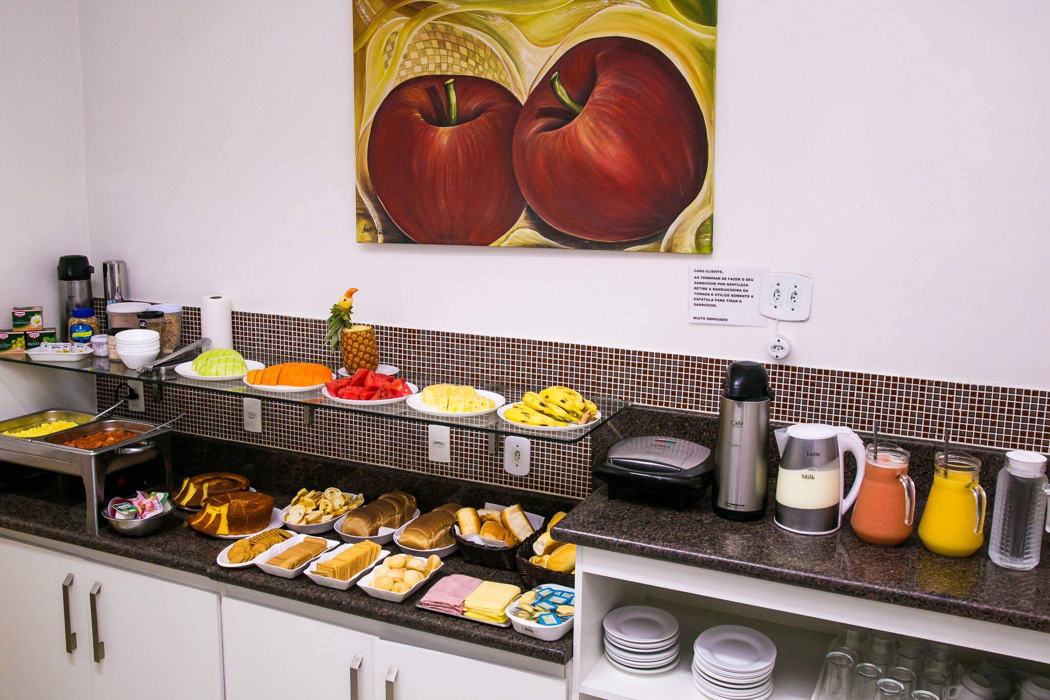 A buffet with various food items, a coffee maker, and a juice dispenser.