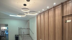 A modern hotel lobby with a staircase, a reception area, and a seating area with chairs. - GV Park Hotel (Governador Valadares)