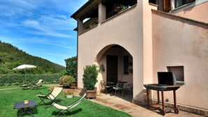 A patio area with outdoor seating, including lounge chairs and tables, and a grill station. - Apartment BERRIES (Agriturismo Il Corniolo) (CORCIANO)