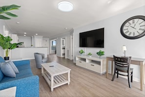 Uma sala de estar moderna com sofá, mesa de centro, TV e uma área de jantar com cadeira e mesa.