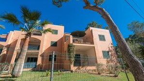 A multi-story building with balconies, a palm tree, and a fence. - BURGIT - Modern apartment located 80 metres from the paradisaical cove of Cala Barca Trenc (Santanyí)