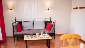 Ein gemütliches Zimmer mit einer Couch, einem Holztisch mit Schachfiguren und einer Kerze auf einem Holztisch.