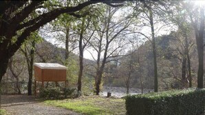 A wooden structure in a forested area with a gravel path and a neatly trimmed hedge. - Camping La Charderie (Pont-de-Labeaume)