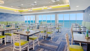 A spacious dining area with multiple tables and chairs, large windows offering a view of the ocean, and a ceiling with recessed lighting. - Gorgeous Modern Ocean View Condo w/ Access to Resort Amenities (Myrtle Beach)