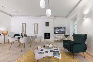 Una sala de estar moderna con chimenea, un comedor con sillas, un sillón verde y una mesa de centro con revistas.