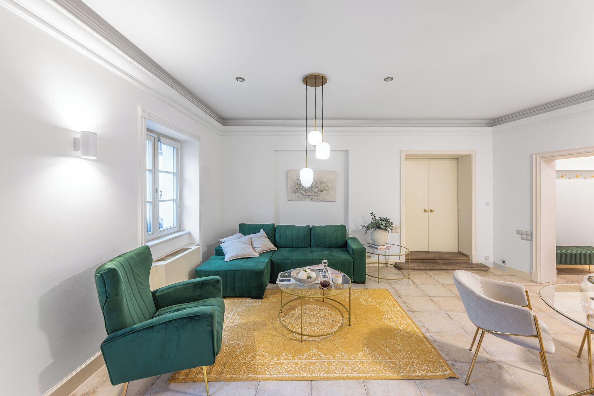 Een moderne woonkamer met een groene zitbank, een glazen salontafel en een geel, gestreept tapijt.