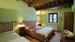 A bedroom with two beds, a window with curtains, a radiator, and a wooden ceiling. - Apartment GRAPE (Agriturismo Il Corniolo) (CORCIANO)
