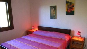A bedroom with a bed, two bedside tables with lamps, and two wall-mounted paintings. - Trilo Bellavista 3 (Olbia)