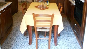 Cocina compacta con una mesa de comedor, sillas, armarios de madera, estufa y un reloj en la pared.