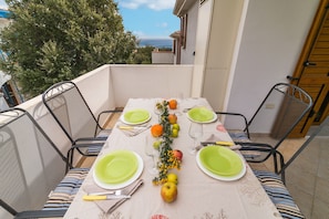 A table set for four with green plates, a vase with flowers, and fruits.