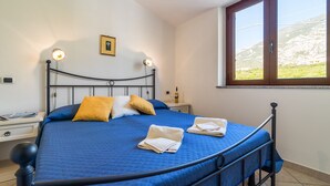 Un dormitorio con cama, almohadas, una mesita de noche y un cuadro en la pared.