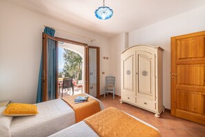 A bedroom with two beds, a wooden wardrobe, and a view of the outdoors. - Casa Festa (Dorgali)