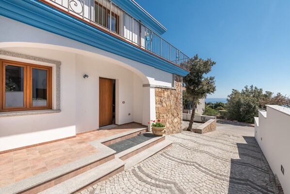 A two-story house with a stone facade, a wooden door, and a blue balcony railing. - Casa Festa (Dorgali)