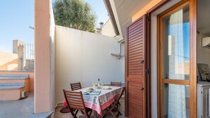 A small outdoor dining area with a table set for two, wooden chairs, and a glass door leading to a covered space. - Casa Tortora (Siniscola)