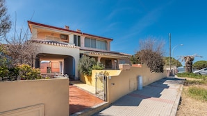A Mediterranean-style house with a tiled roof, a covered porch, and a gated entrance. - Casa Trota (Posada)