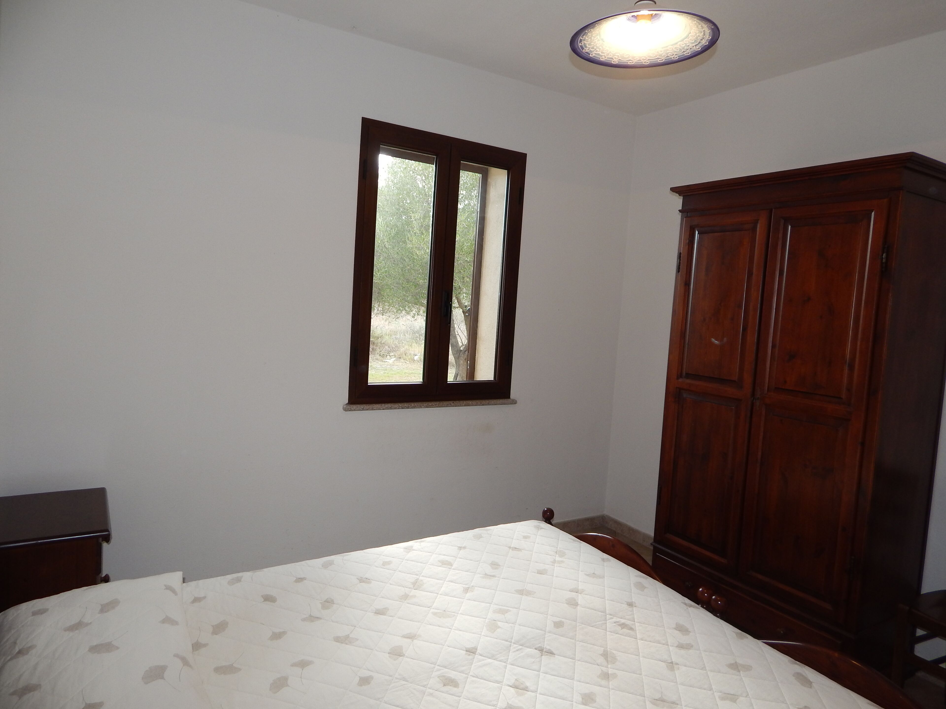 A bedroom with a bed, a wardrobe, and a window.